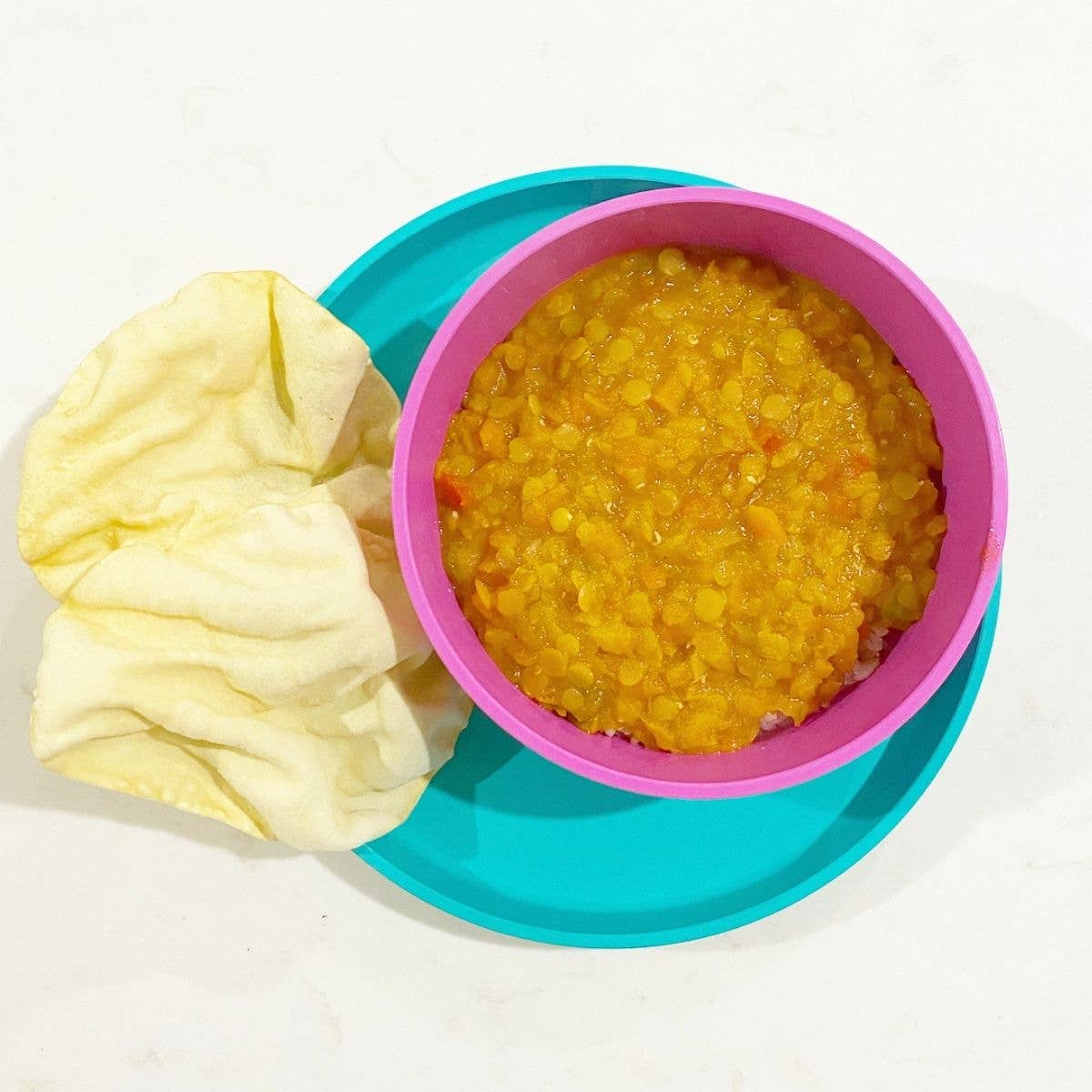 Colorful bowl with yellow food and a yellow napkin on a white background by bobo&boo