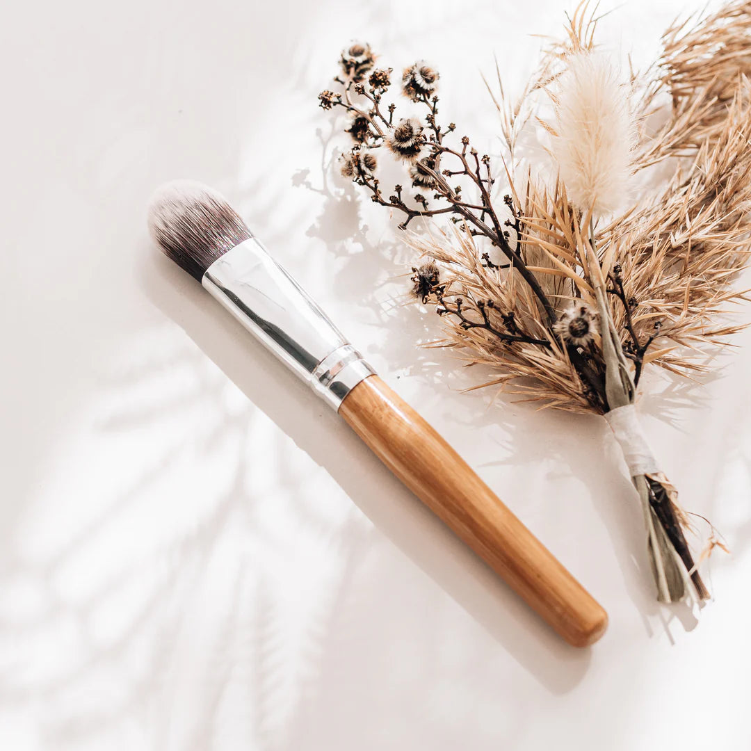 Melvory skincare bamboo brush with wooden handle and dried flowers on a light background