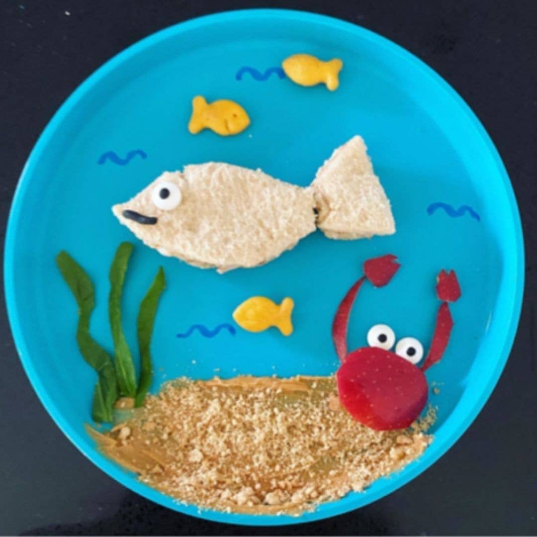 Children's plate with treats shaped like fish, a crab, and seaweed on a blue bobo&boo plate