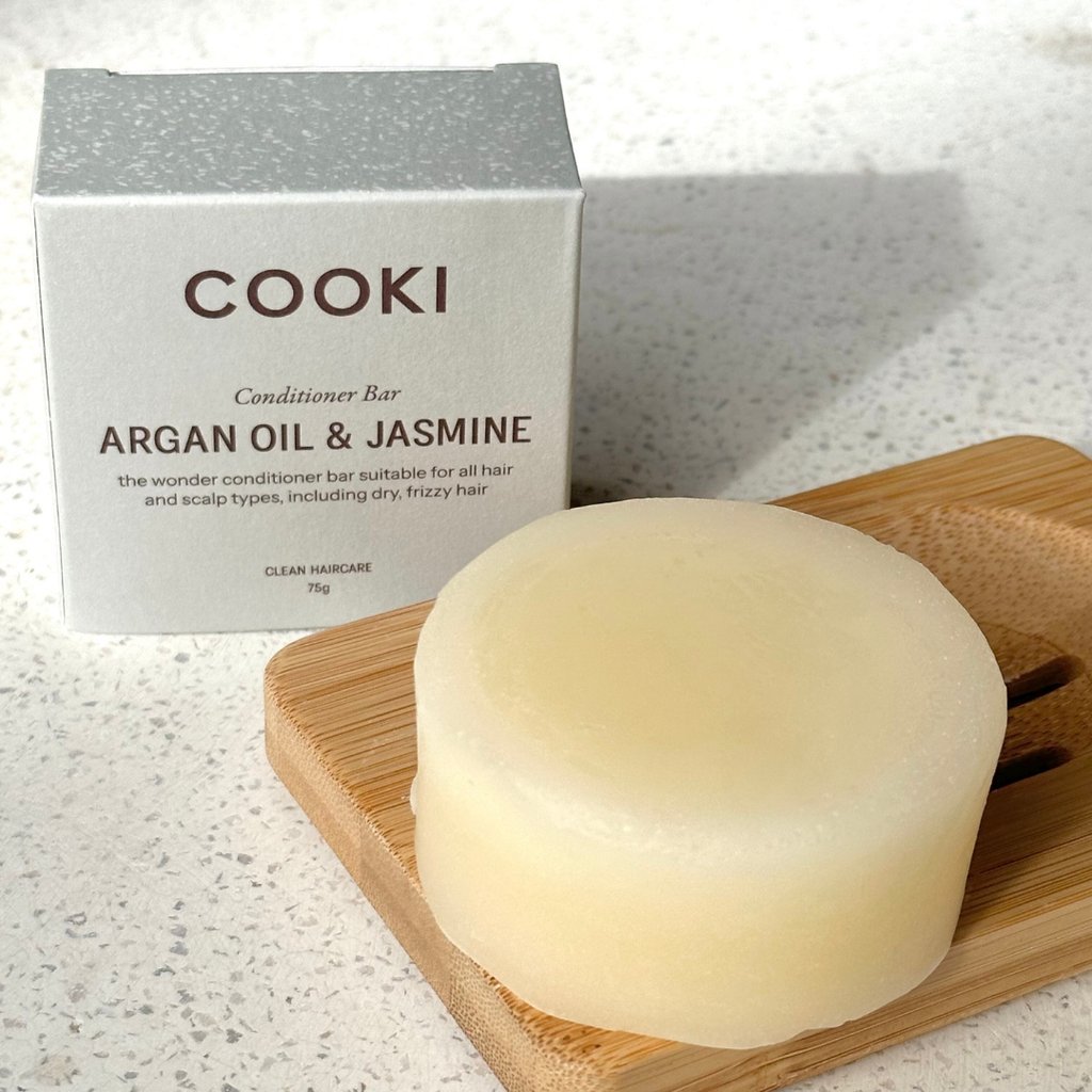Cooki Argan Oil & Jasmine conditioner bar on a wooden tray with packaging in the background.
