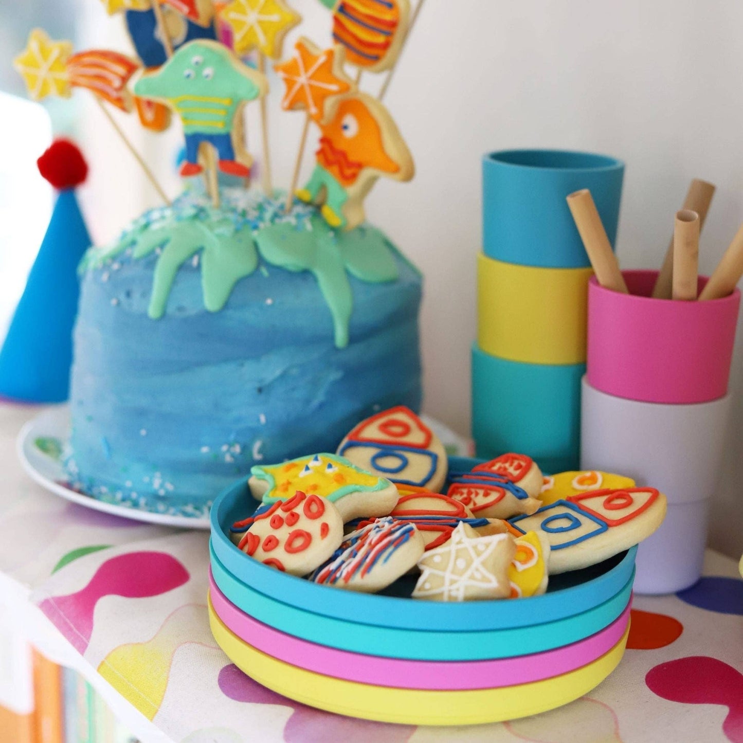 Colorful cake with cookie decorations and party supplies on a table with bobo&boo dinnerware range