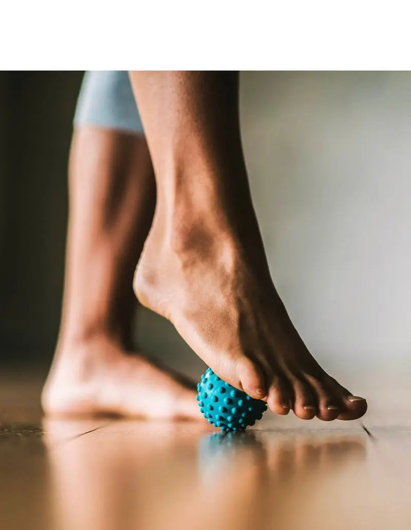 foot and body massager ball being rolled under womens foot