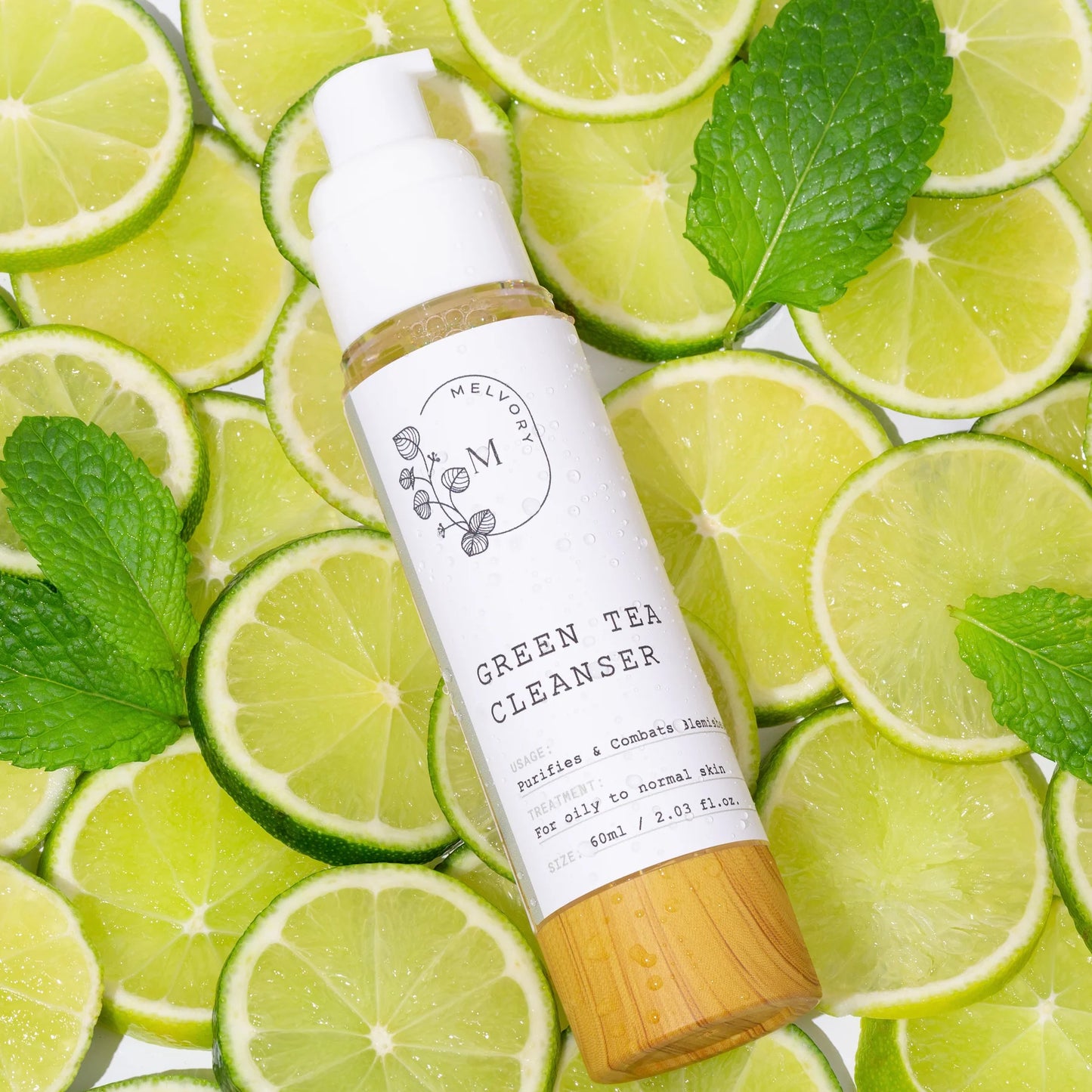 Melvory Green tea cleanser bottle on a background of lime slices and mint leaves