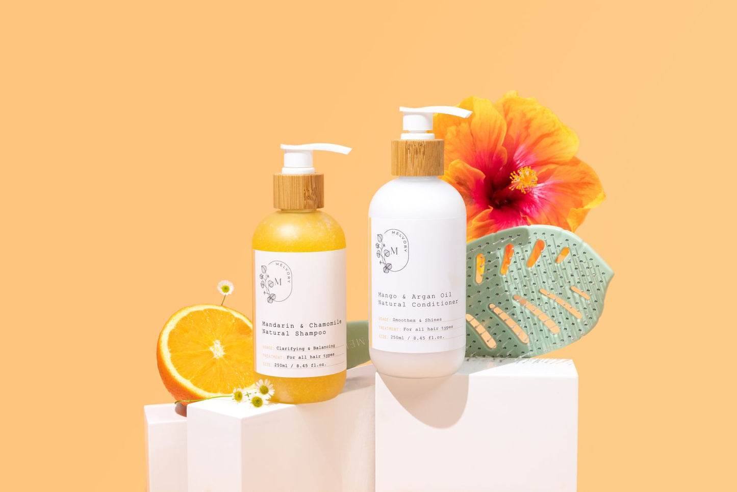 Two bottles of melvory skincare shampoo and conditioner with a colourful flower and orange on a peach background