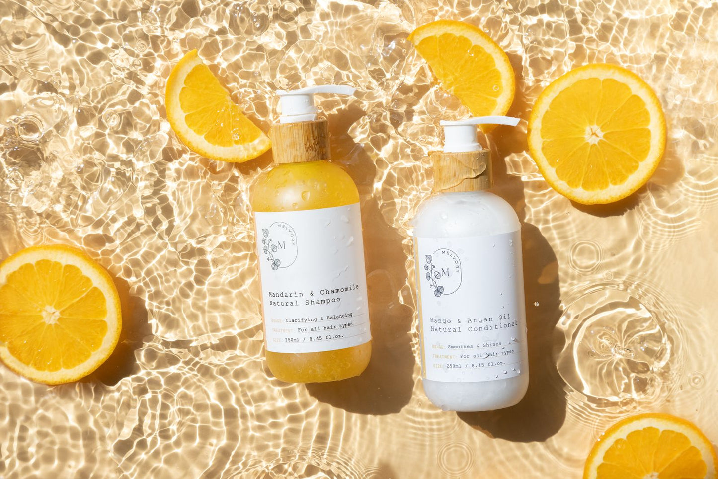Two bottles of Melvory shampoo and conditioner with orange slices on a water surface