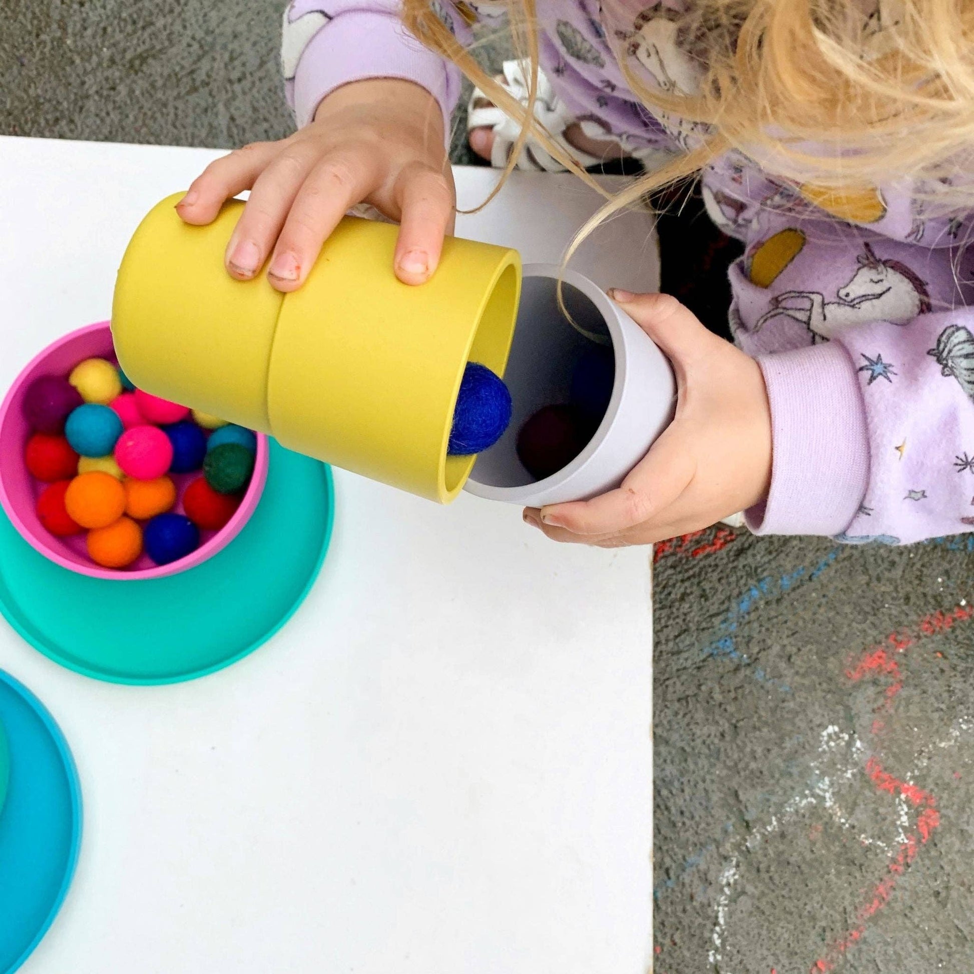 Child playing with colorful bobo&boo  cups and balls on a table