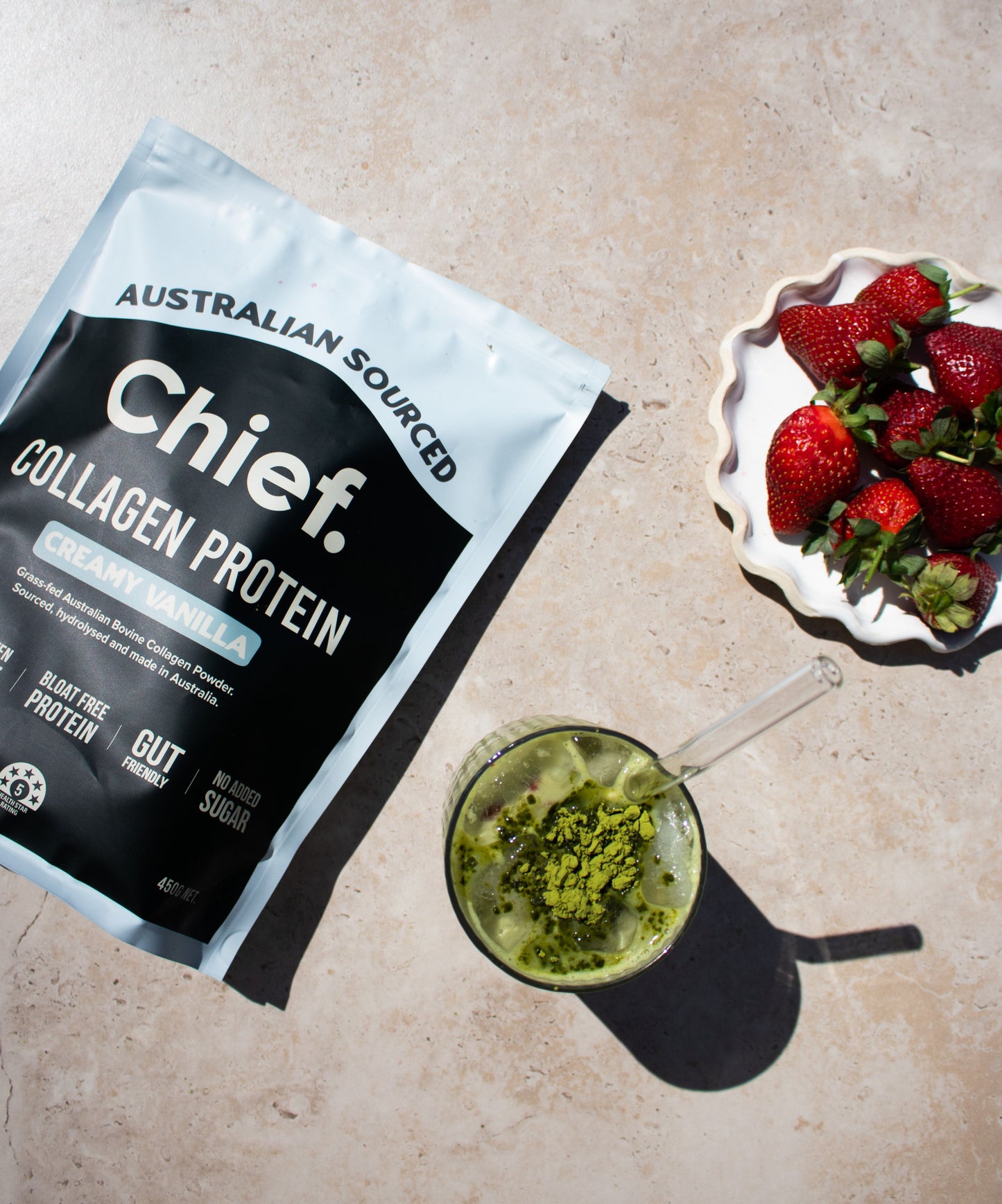 Chief Collagen Protein creamy vanilla flavour package with a green smoothie and strawberries on a beige surface