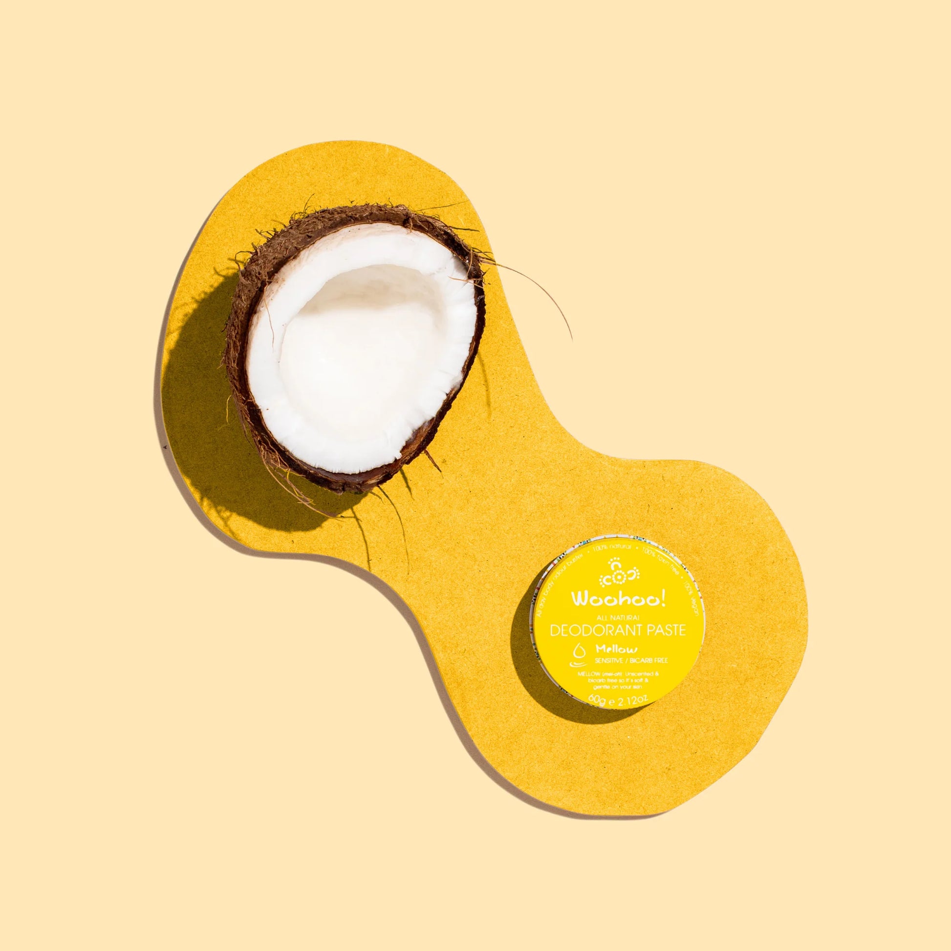 Coconut and a tin of woohoo meloow deodorant paste on a yellow  background 
