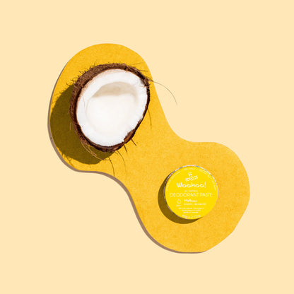 Coconut and a tin of woohoo meloow deodorant paste on a yellow  background 