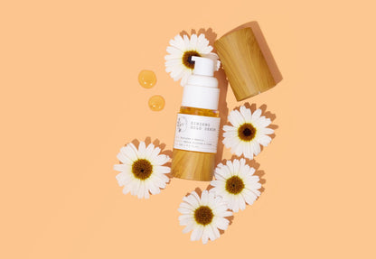 melvory ginseng gold serum and white flowers on a peach background