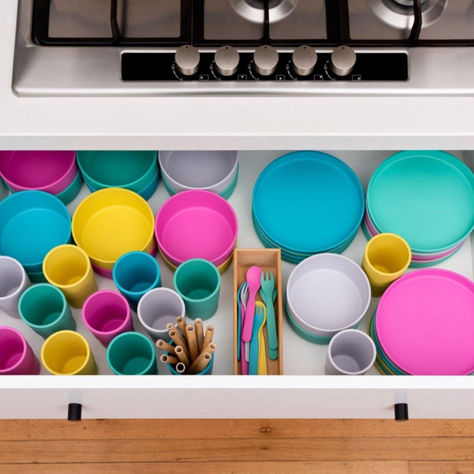 Colorful bobo&boo plant based dishes including plates, cups, and bowls in a kitchen drawer.