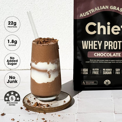 Chocolate protein shake with a package of Australian Grass Chief  Whey Protein Chocolate on a white background.