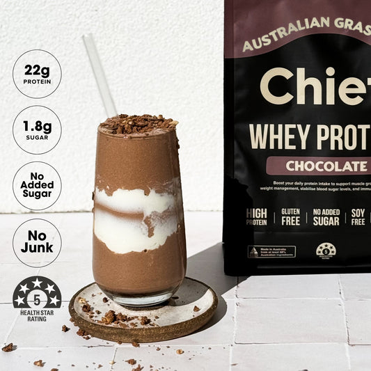 Chocolate protein shake with a package of Australian Grass Chief  Whey Protein Chocolate on a white background.