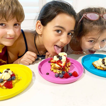 Three children enjoying waffles with fruit on colorful plates from bobo&boo