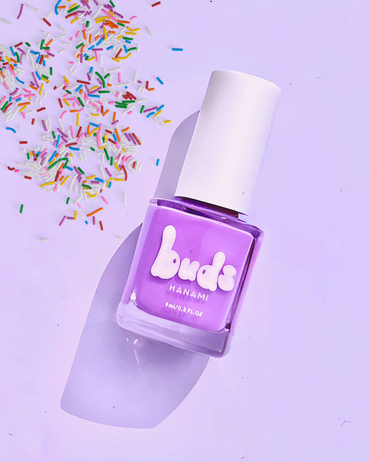 Purple nail polish bottle with hanami 'buds' branding on a light purple background with colorful sprinkles.