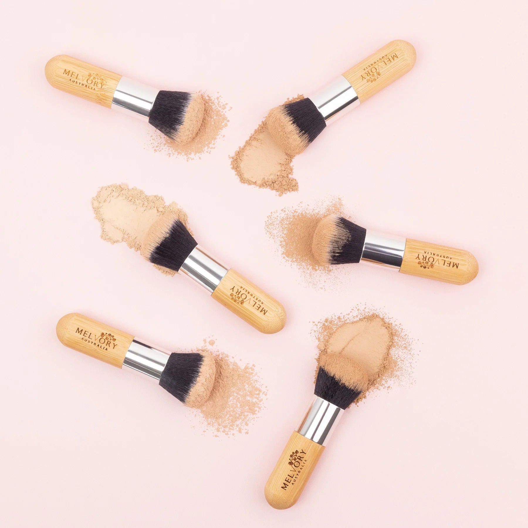 melvory Makeup brushes with powder on a light pink background