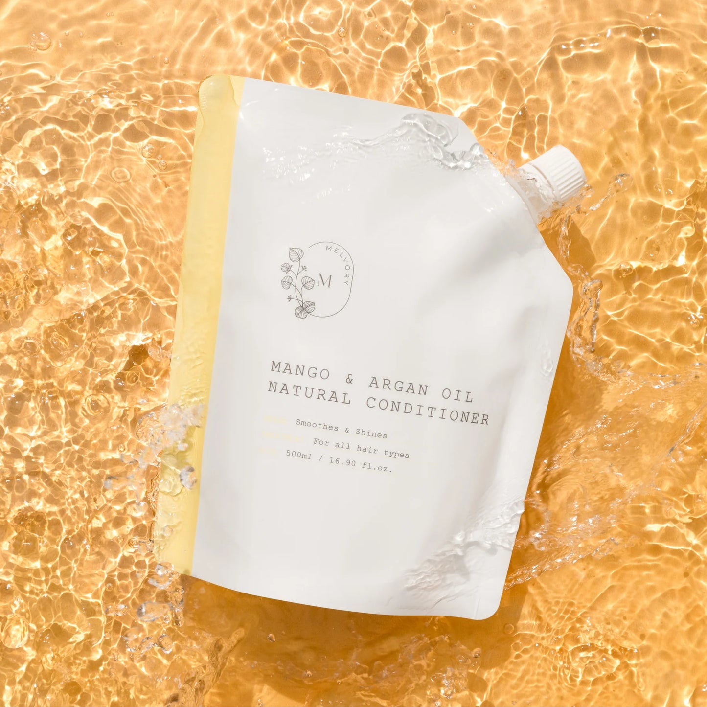 A white stand-up pouch of Melvory Natural Conditioner in Mango & Argan Oil, styled on a golden, water-textured background.