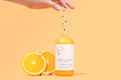 Bottle of Melvory natural shampoo with oranges and flowers on a yellow background