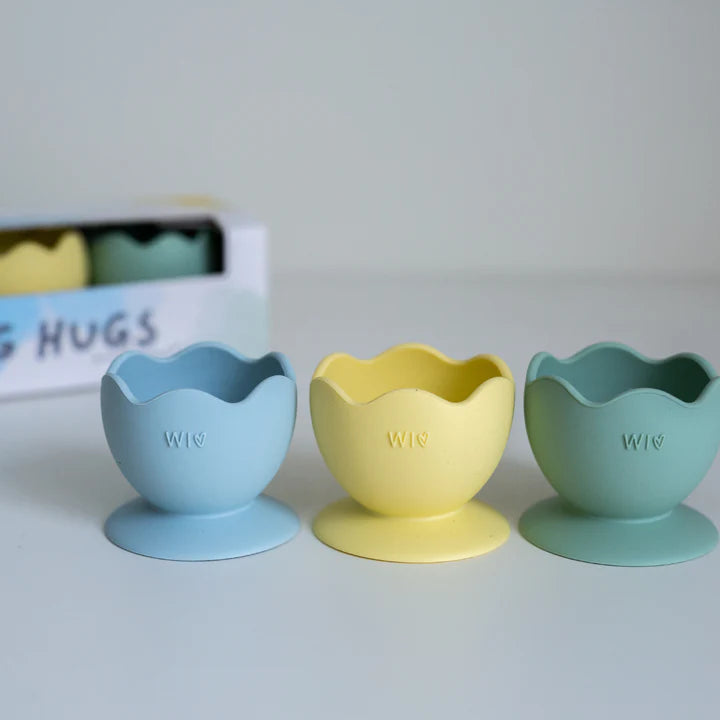 Three colorful silicone egg cups by wild indiana on a light gray background