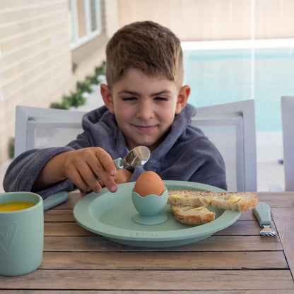 Child sitting at a table with a plate and egg hug from wild indiana 